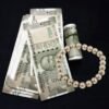 Pyrite Bead Bracelet with Indian currency notes and a pearl necklace on a black background